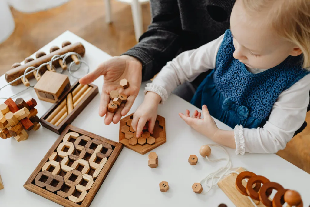 Child engaged in play with wooden educational toys on a table, fostering creativity and learning.