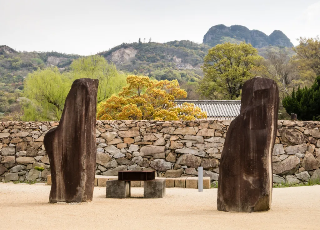 sculptures outside the wall of the outdoor sculpture garden at the isamu noguchi garden museum takamatsu shikoku island japan set against the surrounding mountains