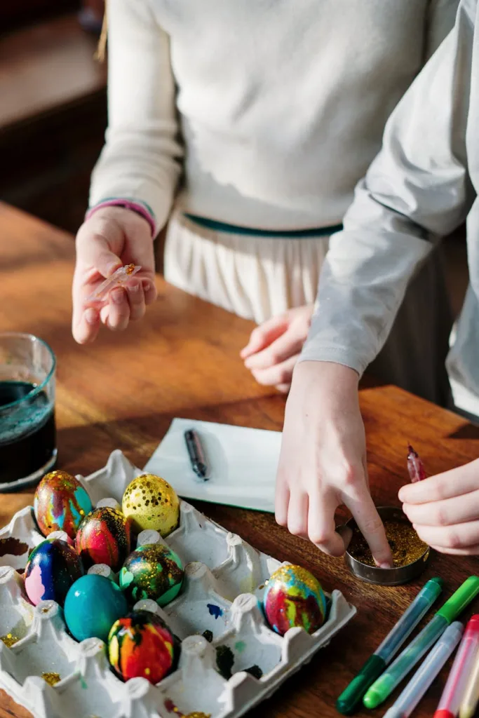 Teenagers creatively decorate colorful Easter eggs with paints and glitter indoors.