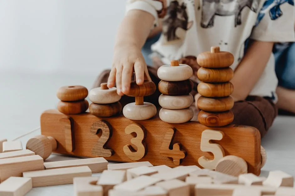 Reggio Emilia vs Montessori: Are They the Same Thing? 5 Child's hand interacting with wooden educational toys and number blocks indoors.